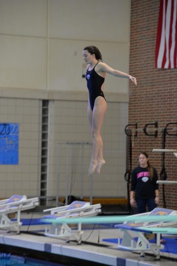 Penny jumps off diving board in meet last January. 